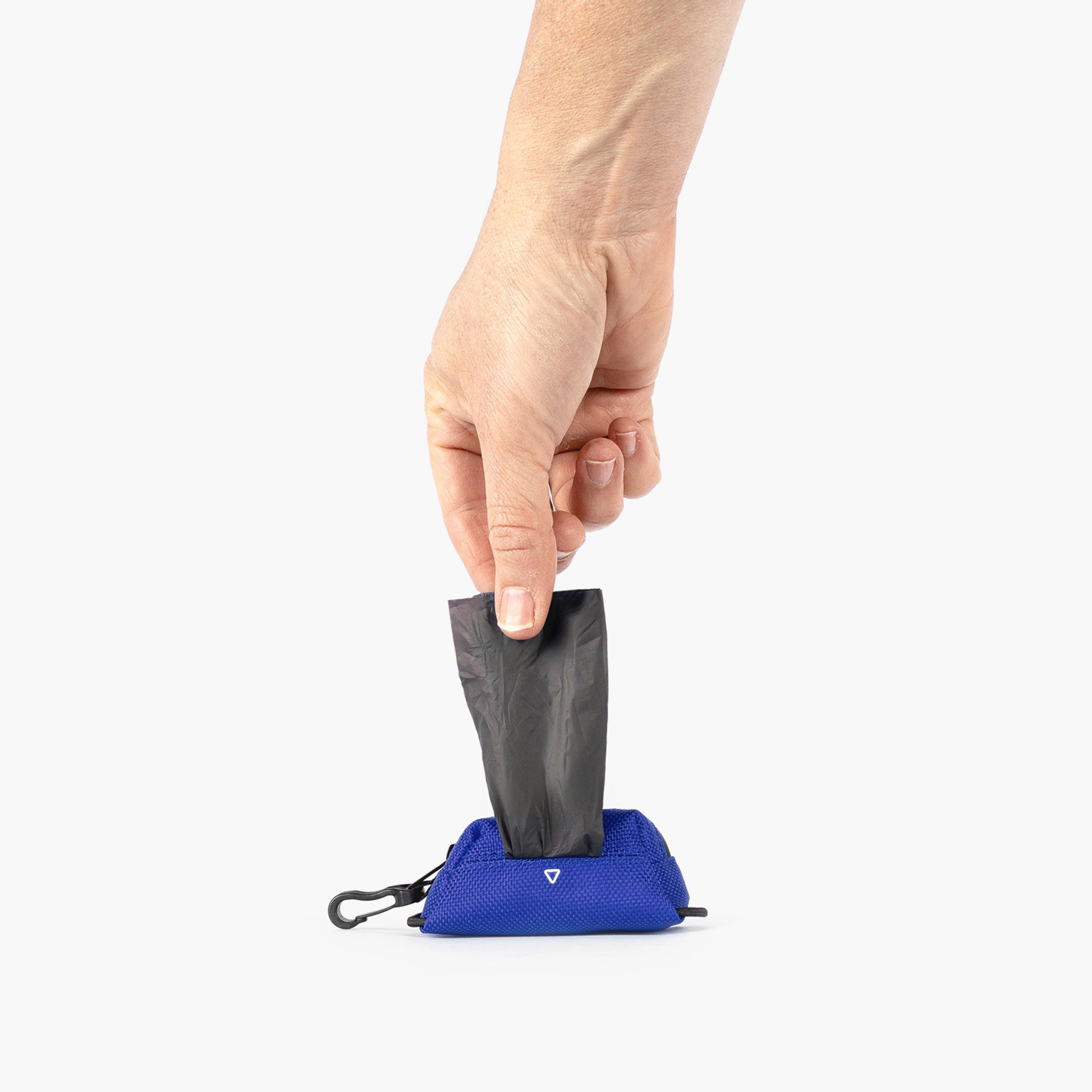 Hand pulling a black trash bag out of a blue Essential Dog Poop Bag Holder on a white background
